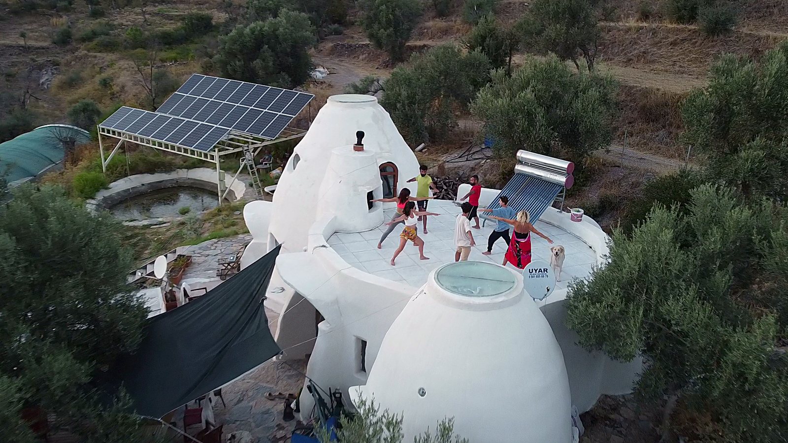Superadobe domes of Lucky Spring Farm at dusk with guests doing a rooftop workout