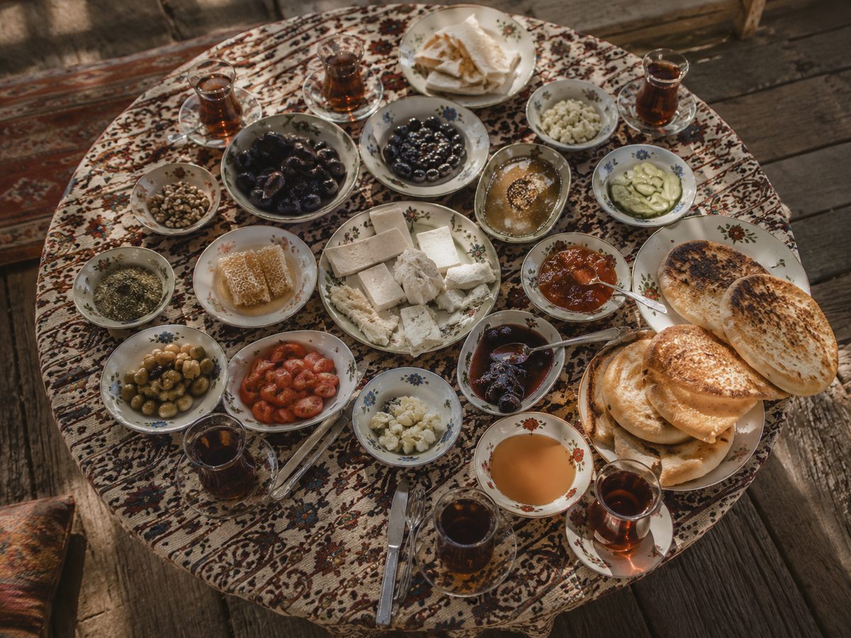 Overhead view of a traditional village breakfast spread with cheese, olives, honey and tea